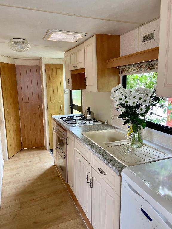 a kitchen with white cabinets and a vase of flowers at U Pani Marioli in Hel