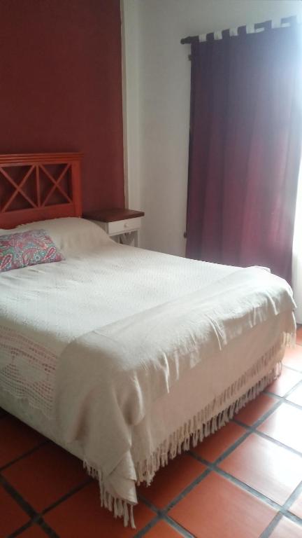 Una cama con una manta blanca encima de una habitación en ALQUILO CASA en gualeguaychú abonas en USD en Gualeguaychú