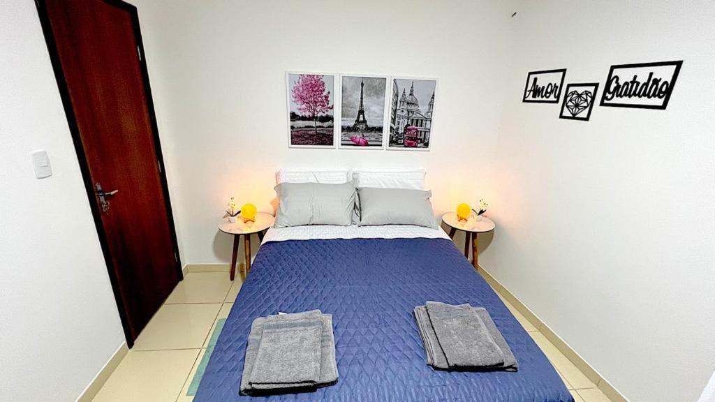 a small bedroom with a blue bed with two tables at Apartamento Perto do Aeroporto in Lauro de Freitas