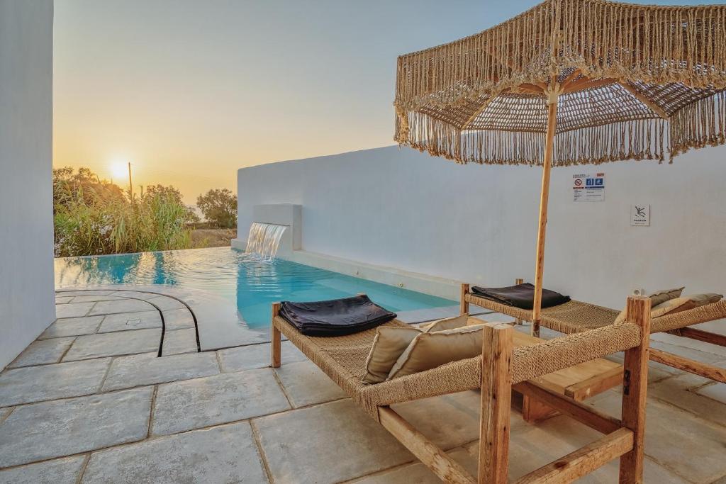 a swimming pool with two chairs and an umbrella at Villa Yialos in Antiparos Town