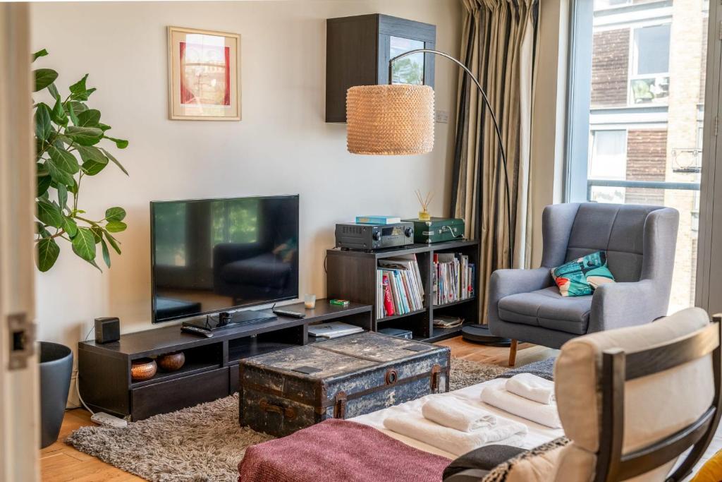 a living room with a couch and a tv at Bright & Spacious Battersea Flat in London