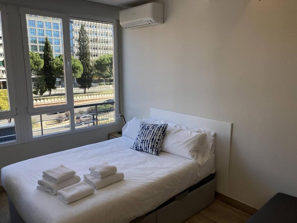 a bed with towels on it in a room with a window at Castellana 4 torres Apartments in Madrid