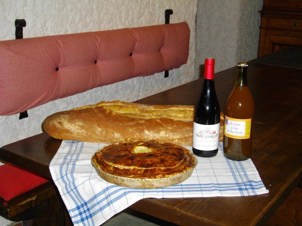 a table with a pizza and two bottles of wine at Gîte du Domaine de Chateux in Soumans