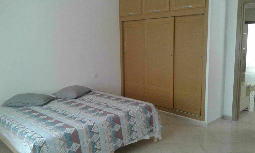 1 dormitorio con 1 cama y armario de madera en Route de la plage, en Kelibia