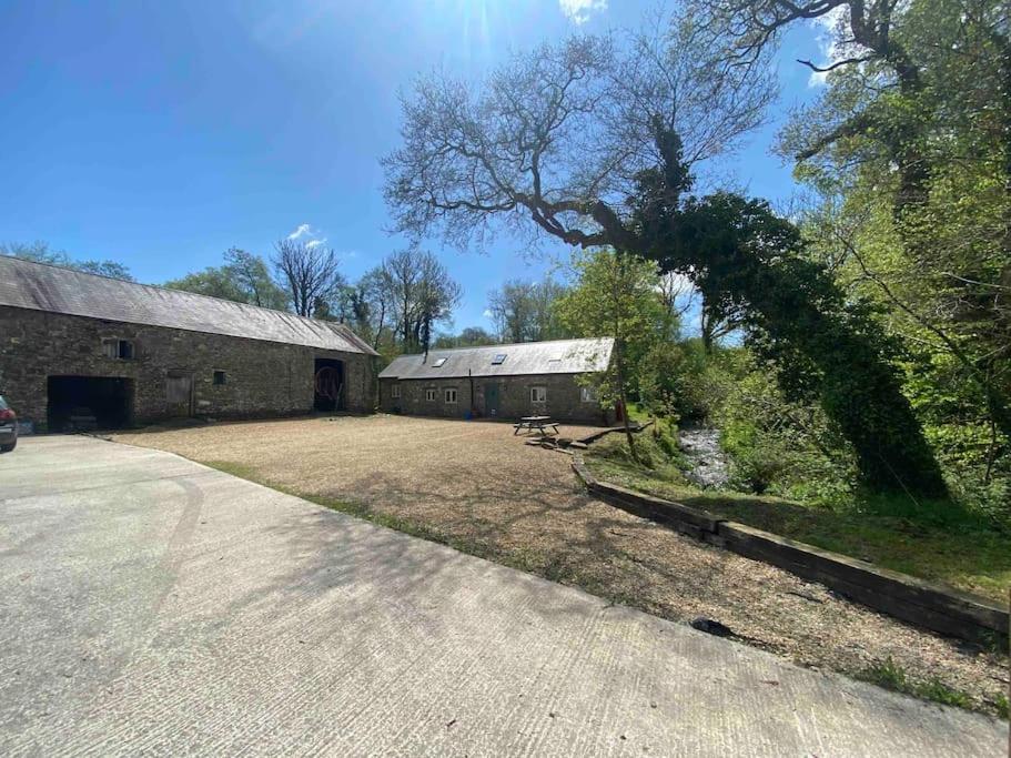 um grande celeiro com uma grande árvore ao lado de uma entrada em Abercrymlyn barn em Llanwrda