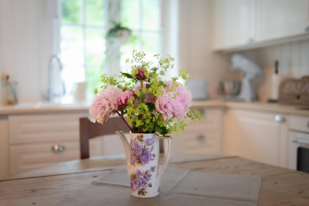 un jarrón lleno de flores rosas y blancas sobre una mesa en Historisk sjarm - moderne komfort 10min fra Bergen, en Bergen