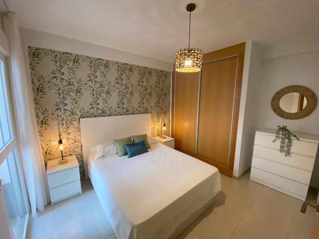 ein Schlafzimmer mit einem weißen Bett und zwei Nachttischen in der Unterkunft Lagunas Home, bajo con terraza al lado de la playa in Vera