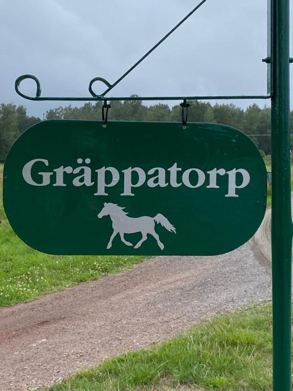 a green sign with a horse on a road at Liten stuga mitt i naturen på Kinnekulle in Hällekis
