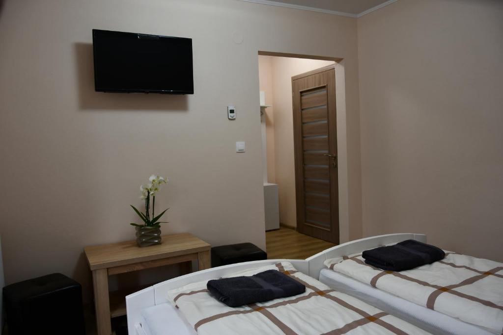 two beds in a room with a television on the wall at Terra Panzió in Corund