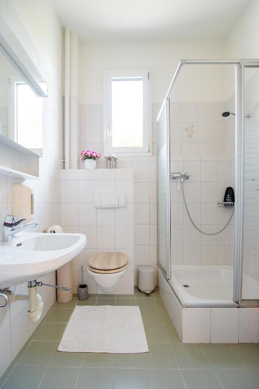 a white bathroom with a shower and a sink at Pensione Solaria in Locarno