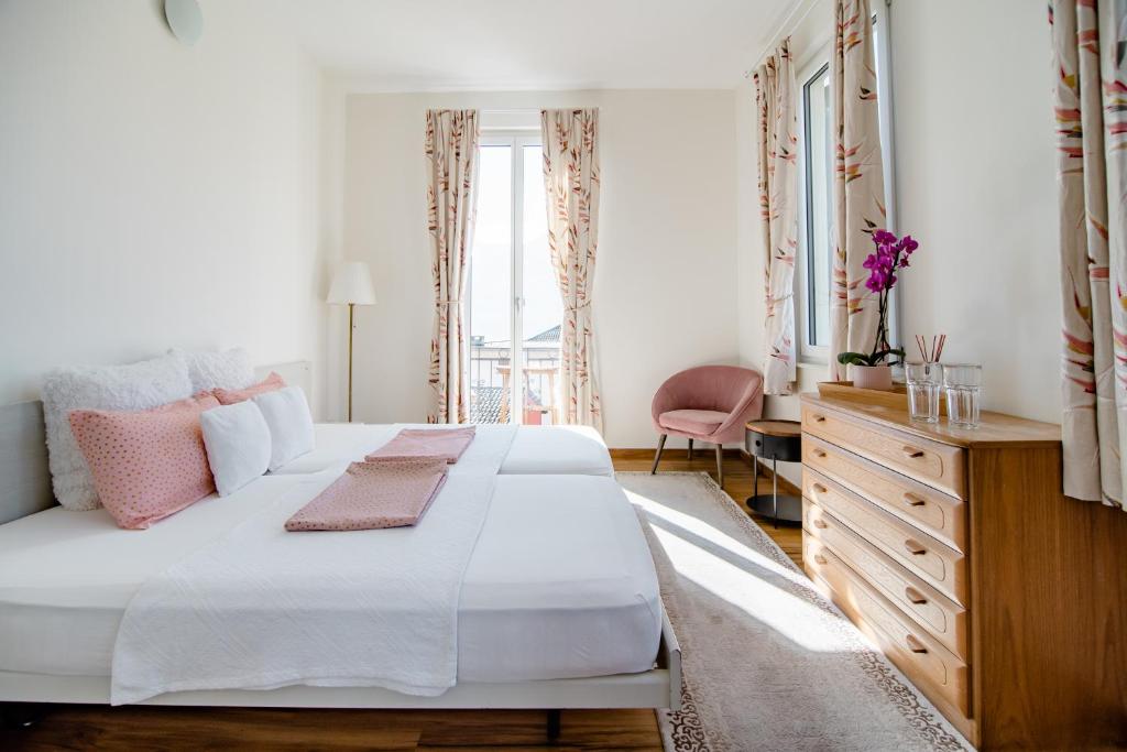 - une chambre avec un grand lit blanc et une commode dans l'établissement Pensione Solaria, à Locarno