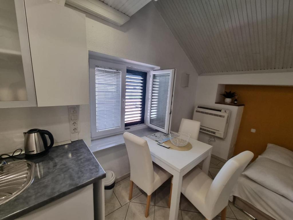 una pequeña cocina con mesa blanca, sillas, mesa y mesa en Guesthouse Lion, en Split