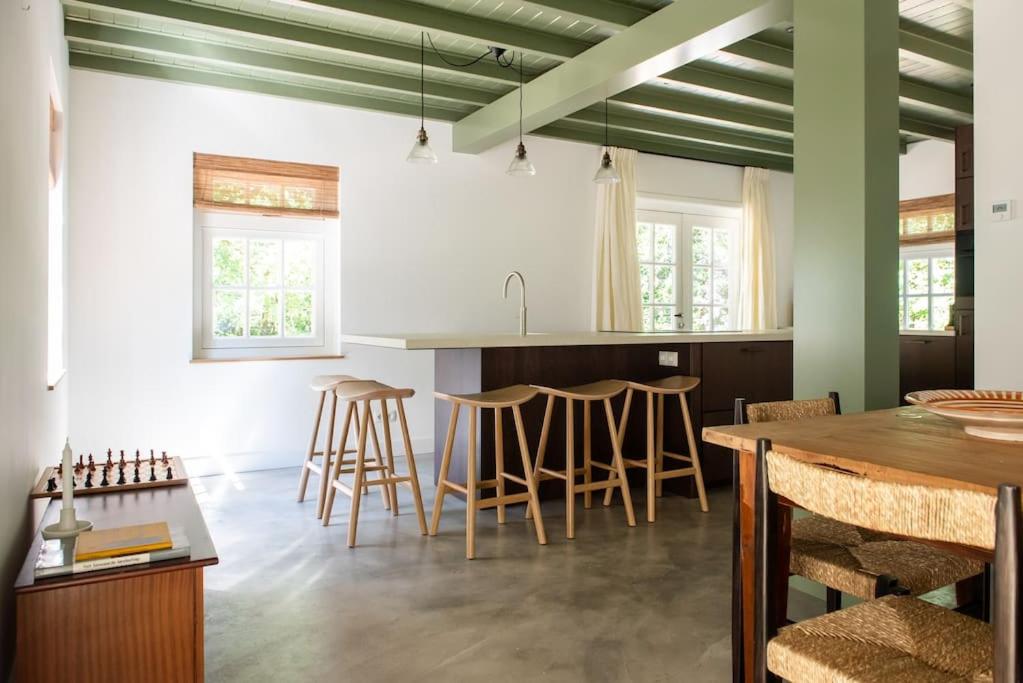 a kitchen with green and white walls and a table and stools at Fantastisch familiehuis met grote tuin I Bosrijk in Lunteren