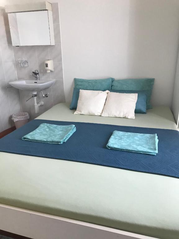 a bed with two pillows and a sink in a room at Pensione Solaria in Locarno