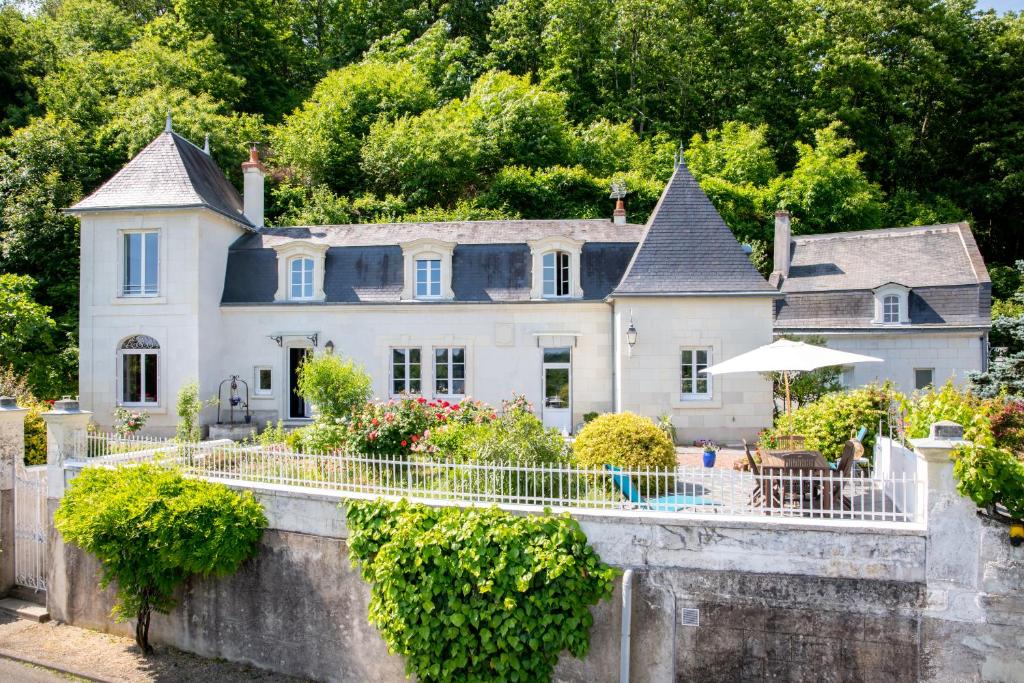 a house on a hill with a stone wall and trees at Le Clos Eugénie in Gennes