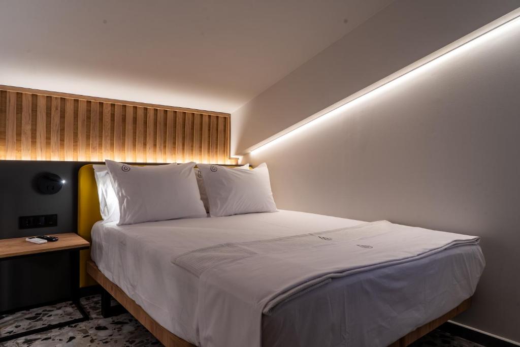 a bedroom with a large bed with white sheets at NERO SEASCAPE SUITES in Fanari