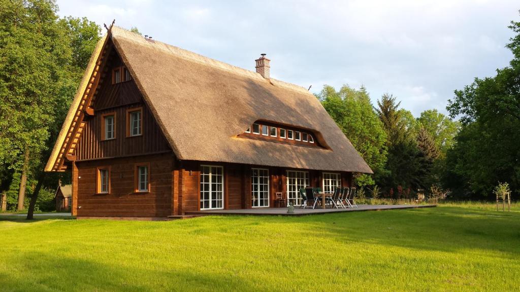 una casa con techo de paja en un campo de césped en Exklusives Holzhaus, en Burg