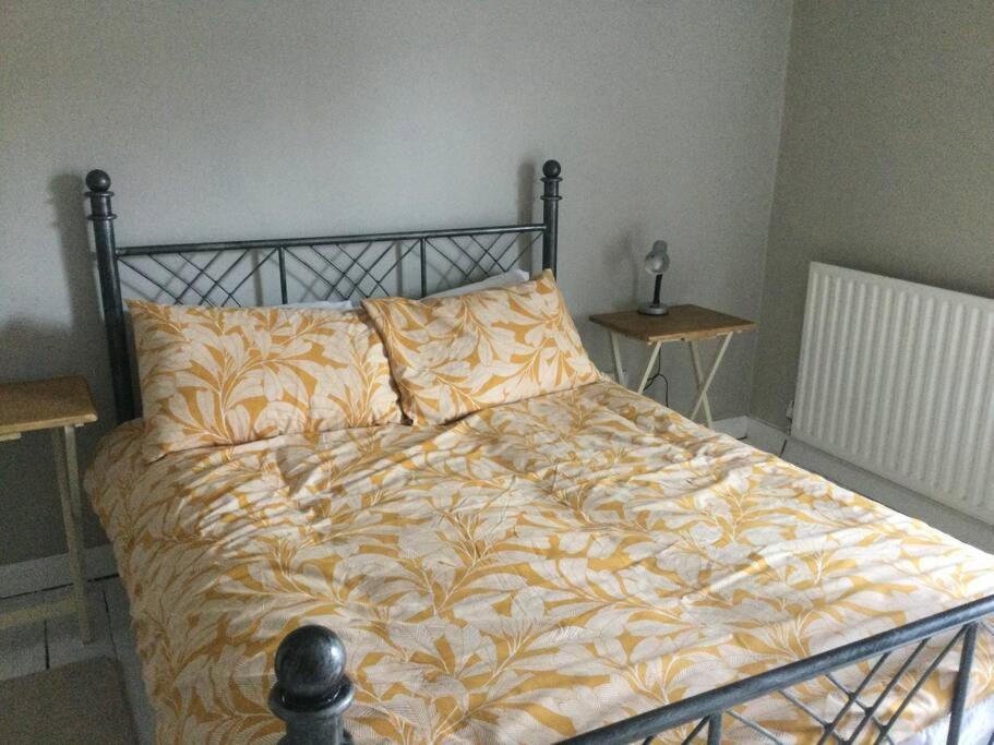 a bedroom with a bed with a yellow blanket and two tables at 3 Bed Home on Edge of Lake District in Winder