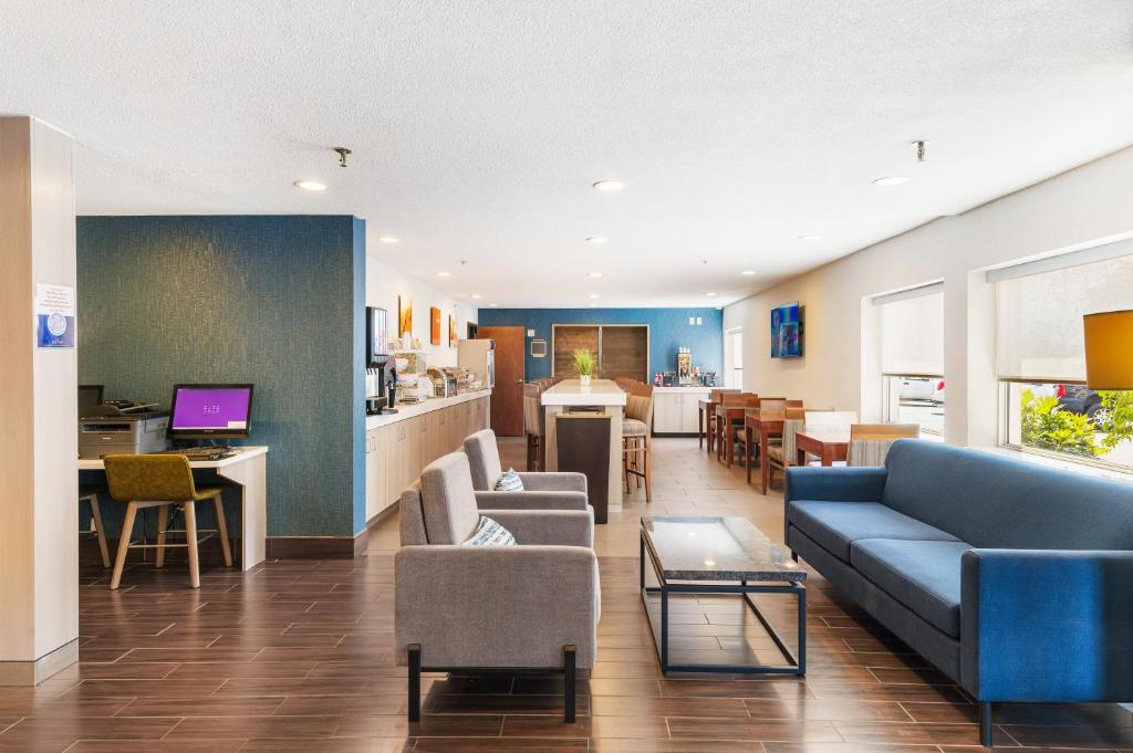 a living room with a blue couch and a kitchen at Comfort Inn Mayfield Heights Cleveland East in Mayfield