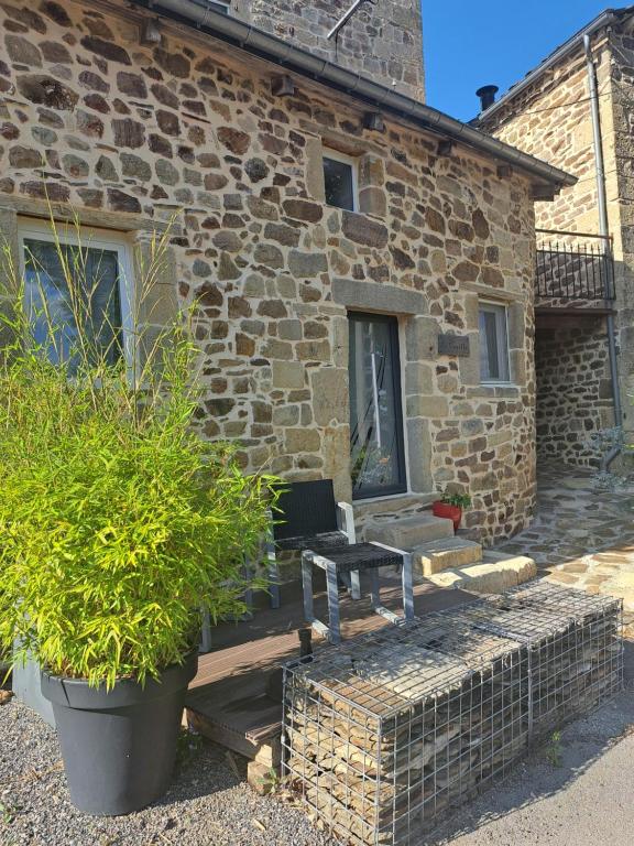 ein Steinhaus mit einer Bank davor in der Unterkunft La cazette in Recoules-Prévinquières