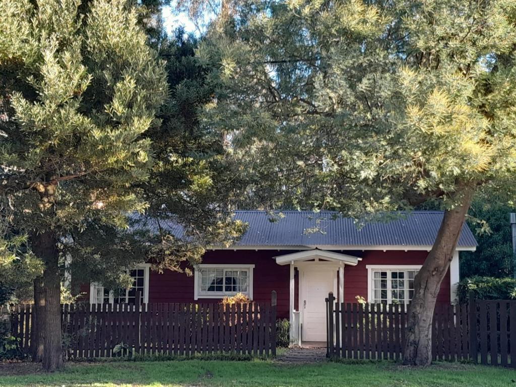 una casa roja con una valla y árboles en Cabaña Sueca, en Mar del Plata