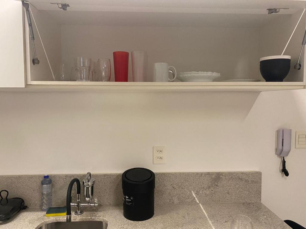 a kitchen counter with a sink and a shelf with dishes at Apartamento novo de alto padrão e aconchegante#224 in Brasilia