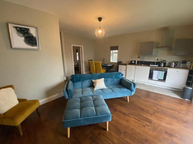 a living room with a blue couch and a kitchen at Fort Mews in Ballina