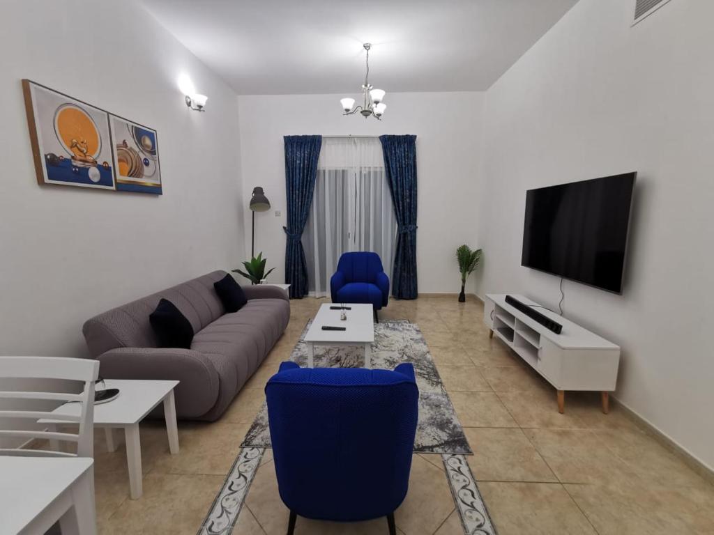 ein Wohnzimmer mit einem Sofa und einem TV in der Unterkunft Khan Property in Schardscha
