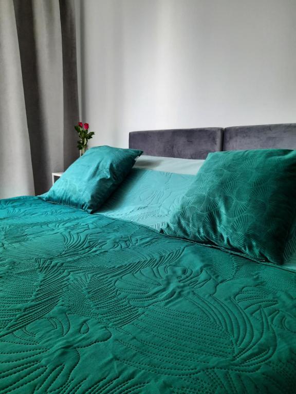 a green bed with green sheets and pillows at Apartament Nowa letnica in Gdańsk