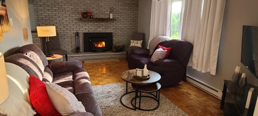 a living room with two couches and a fireplace at Lush's Lodge in Cormack