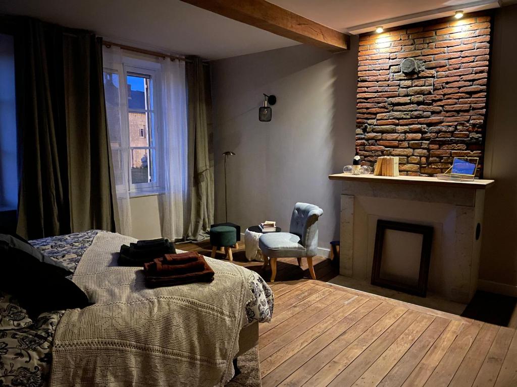 a bedroom with a fireplace and a bed and a chair at Maison Longue de La Cassine in Vendresse