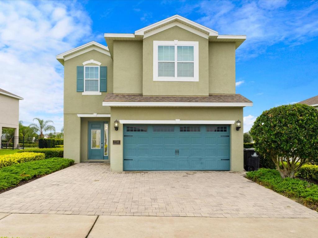 een huis met een blauwe garagedeur bij Modern Home With Private Pool Near Disney By Encore Resort At Reunion by Rentyl - 7738F in Orlando