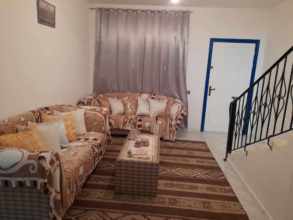 ein Wohnzimmer mit 2 Sofas und einem Tisch in der Unterkunft Maison à Hergla, Sousse, Tunisie in Harqalah