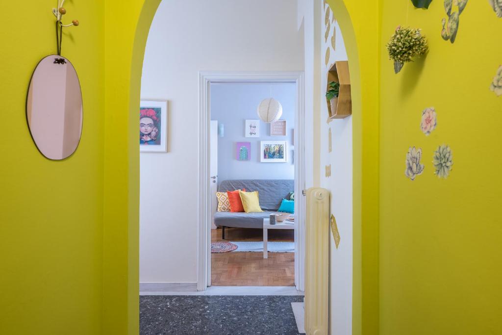 a hallway with yellow walls and a room with a couch at Sweet home in Koukaki in Athens