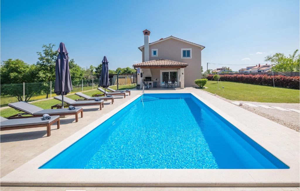 a swimming pool with chairs and a house at 3 Bedroom Stunning Home In Zminj in Žminj