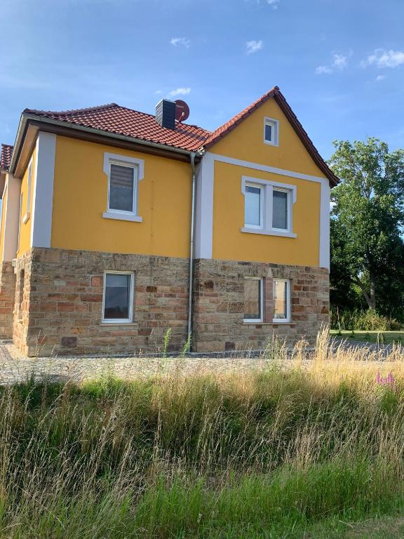 ein gelbes Haus am Rand eines Feldes in der Unterkunft Ferienwohnung Malisa in Bad Bibra