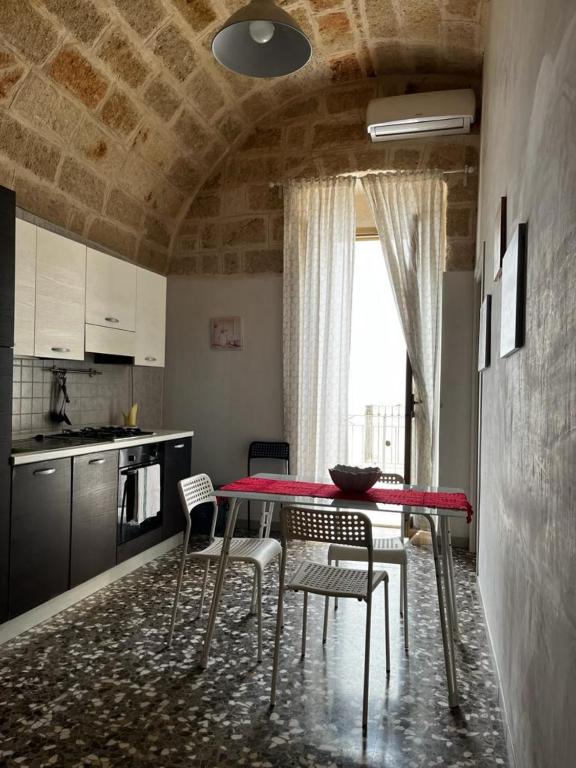 a kitchen with a red table and chairs in a room at La Dimora di Nonna Lucia in Polignano a Mare