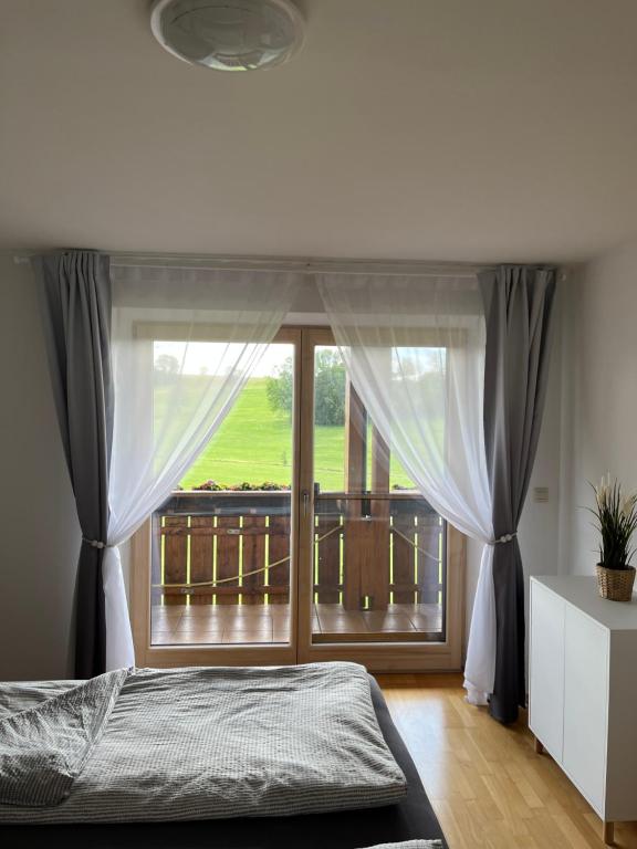 um quarto com uma cama e uma grande janela em Ferienwohnung Sonnenstrahl em Friesenried