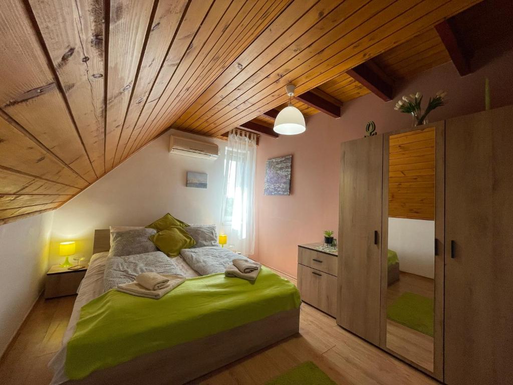 een slaapkamer met een groot bed en een houten plafond bij Linett Apartman in Hajdúszoboszló