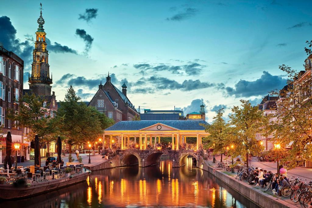 a building with a bridge over a river in a city at Leiden City Centre Canal View or Terrace View Apartments in Leiden