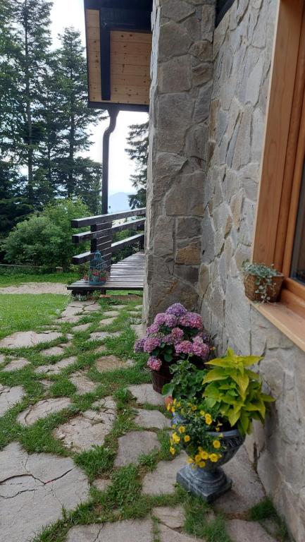 a stone building with a bunch of flowers next to a porch at Rogla - Chalet Mojca Pokrajculja in Zreče