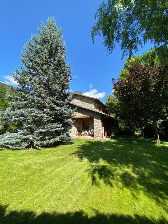 a stone house in a field with a tree at Casa Marian Villanua in Villanúa