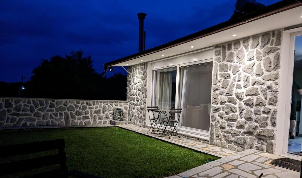 a stone house with a table in the yard at night at Ethos Apartment 2 in Néa Péramos