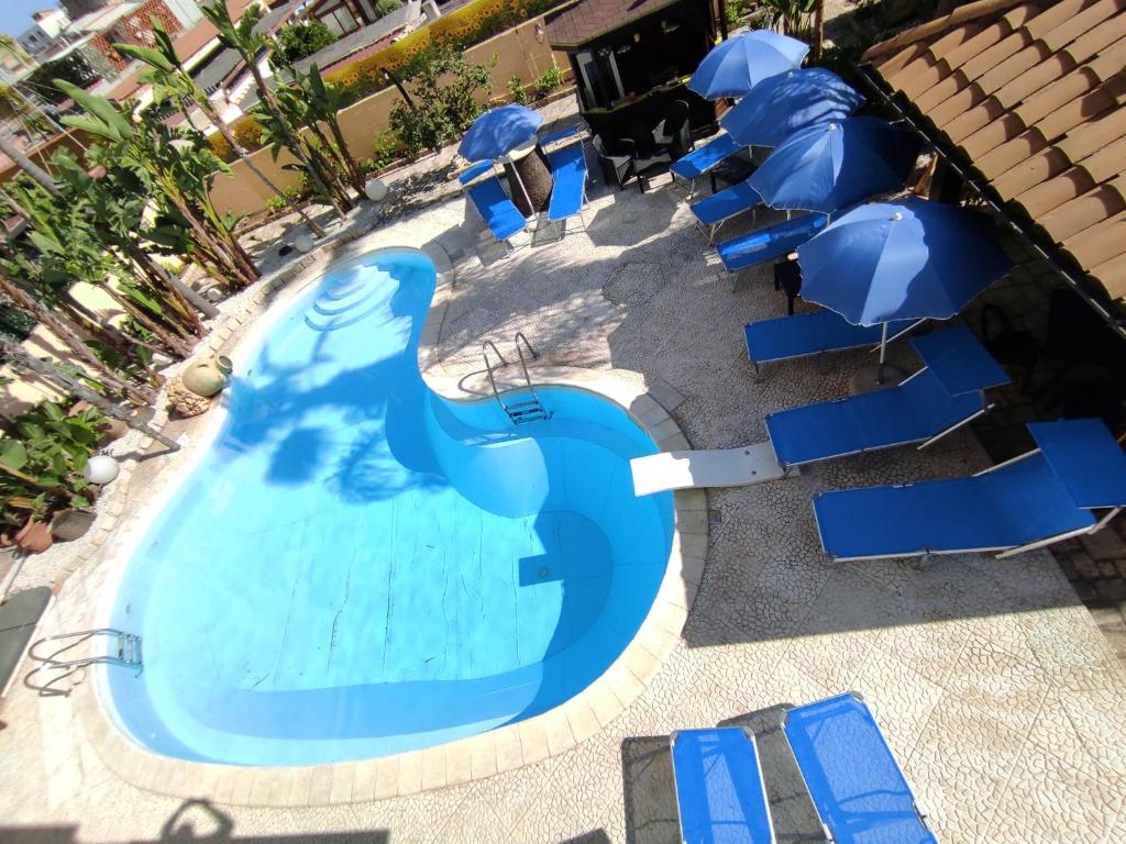 an empty swimming pool with blue chairs and umbrellas at B&B Villa Colomba in Agrigento