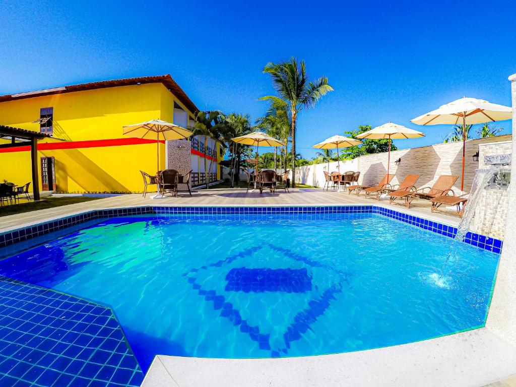 uma grande piscina com cadeiras e guarda-sóis em Bem Bahia Hotel - Rede Bem Bahia em Porto Seguro