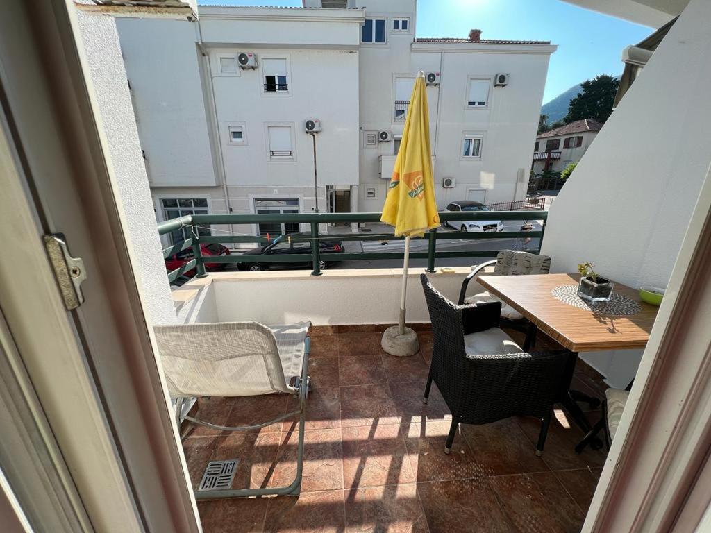 einen Balkon mit einem Tisch und einem gelben Regenschirm in der Unterkunft Milinovic apartmani1 in Herceg-Novi