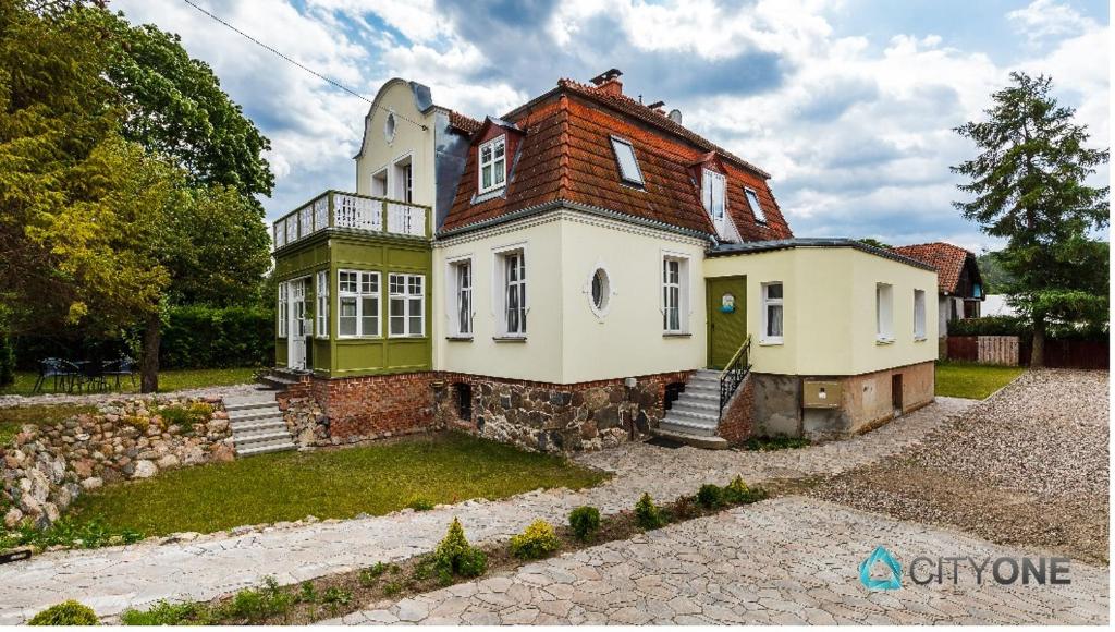 een groot huis met groen en wit bij Apartament z Werandą w Dworku Oliwskim in Gdańsk