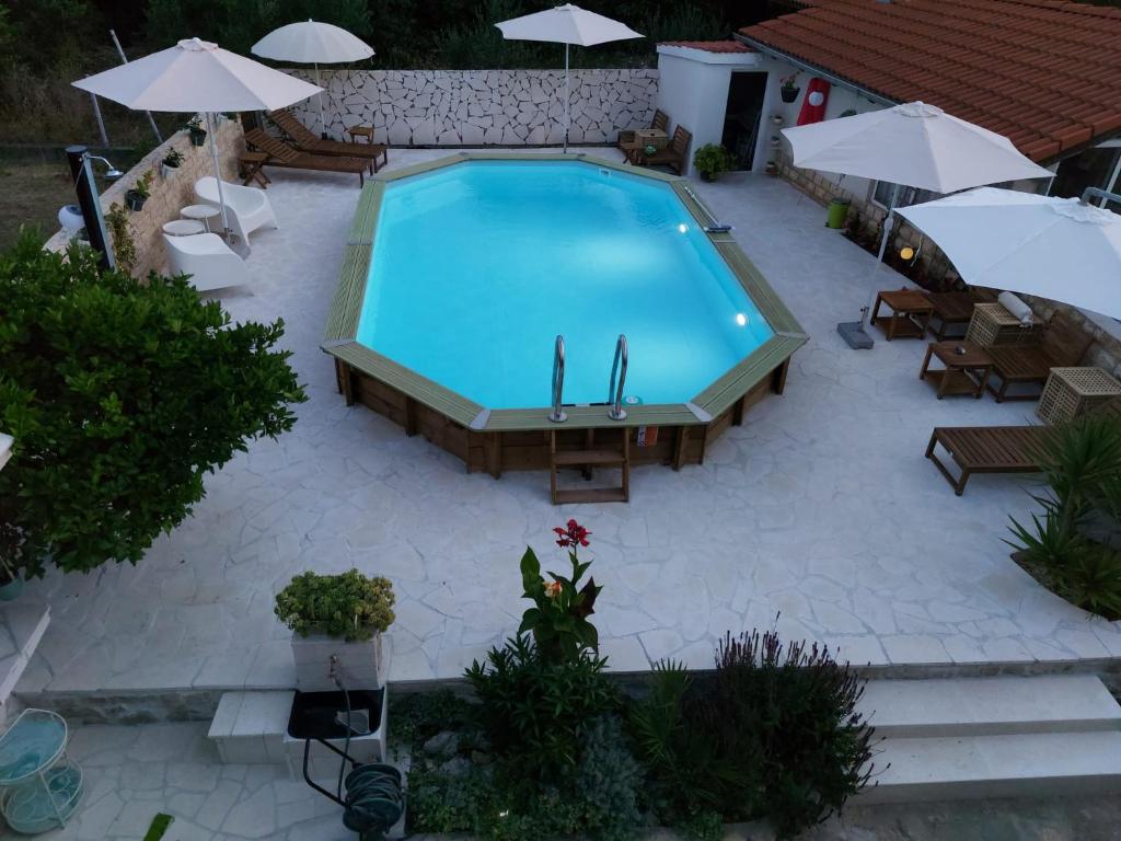 eine Draufsicht auf einen Swimmingpool mit Stühlen und Sonnenschirmen in der Unterkunft Apartmani Merica in Pakoštane