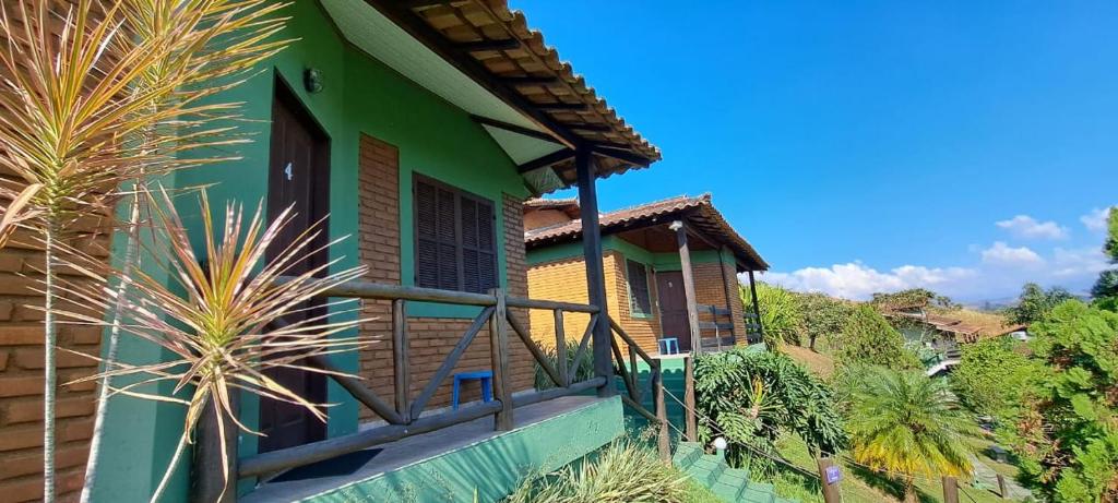 a house with a green facade and a balcony at Pousada Cheiro de Mato in Penedo