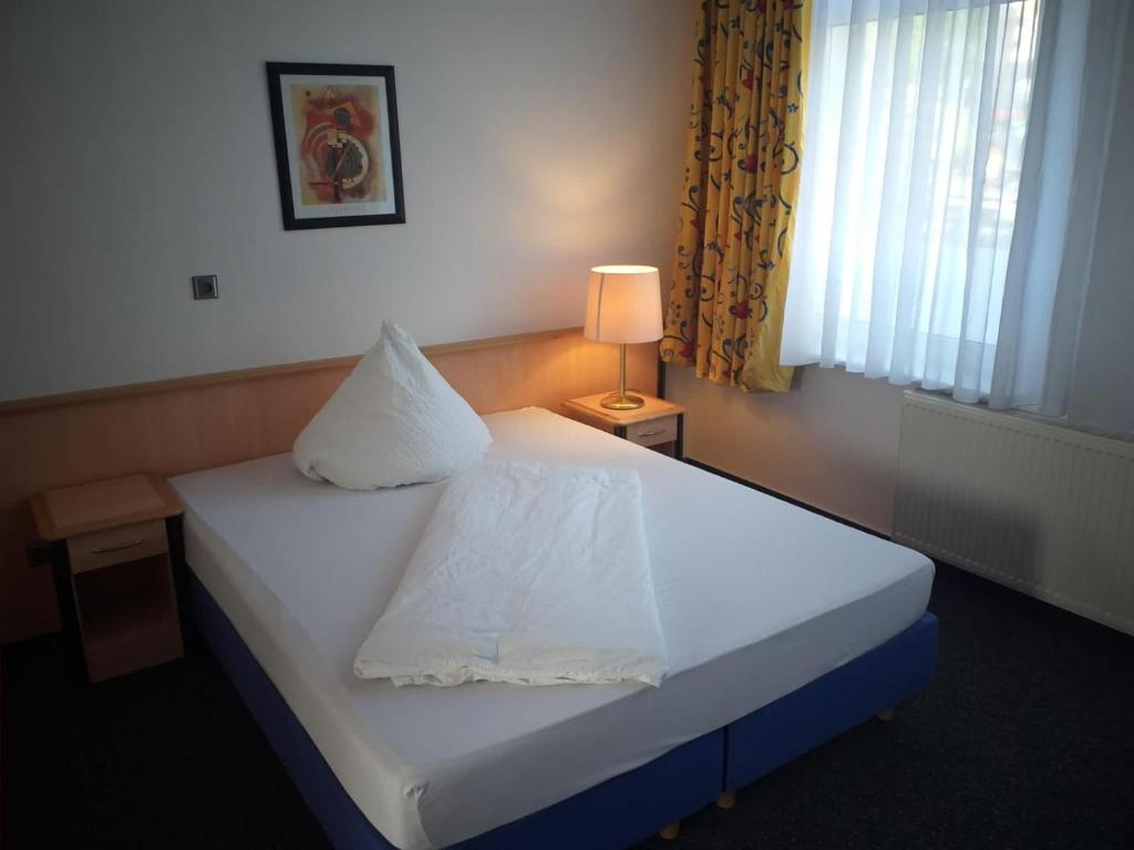 1 dormitorio con 1 cama blanca con lámpara y ventana en Gästezimmer Gasthof Becker, en Wülfrath